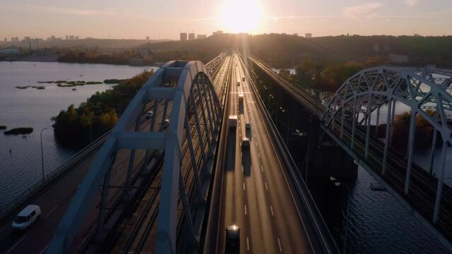 Aerial perspective view of urban bridge over the river. Evening sunset light reflecting on the road.