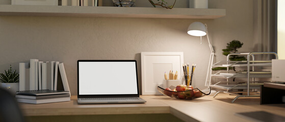 Comfortable and minimal working space with laptop mockup, table lamp, stationery on wood table