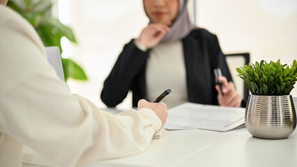 Close-up shot of a female office employee is in the meeting with her Muslim boss.