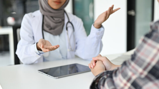 cropped image, A professional Asian Muslim female doctor talking with a patient in the office