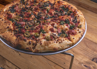 Pizza a la leña con ingredientes variados como carne, cebolla, pimiento, chorizo, jamón. 