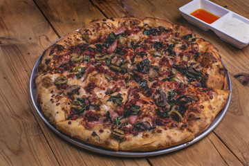 Pizza a la leña con ingredientes variados como carne, cebolla, pimiento, chorizo, jamón. 