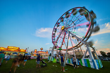 Carnival county fair with ferris wheel attraction at dusk - obrazy, fototapety, plakaty