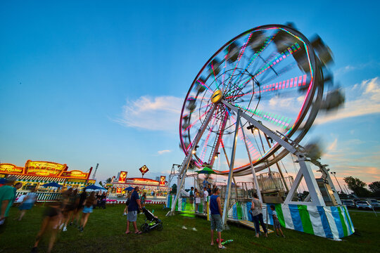 Carnival County Fair With Ferris Wheel Attraction At Dusk