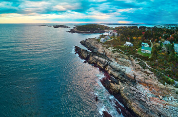 Fototapeta premium Ocean and rocky coast of Maine aerial with houses and trails