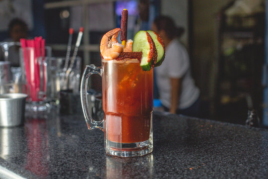 Deliciosa michelada preparada con pepino, camar&oacute;n, chile chamoy, apio y clamato