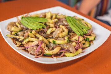 Plato de mariscos bañado en salsa inglesa con aguacate, cebolla y limón