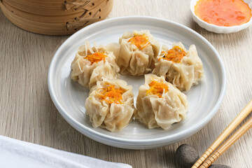 Steamed dumpling dimsum served in plate with chilli sauce