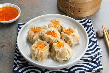 Steamed dumpling dimsum served in plate with chilli sauce
