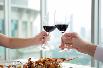 Hands of young couple holding with glass of wine cheer together in anniversary at restaurant for...