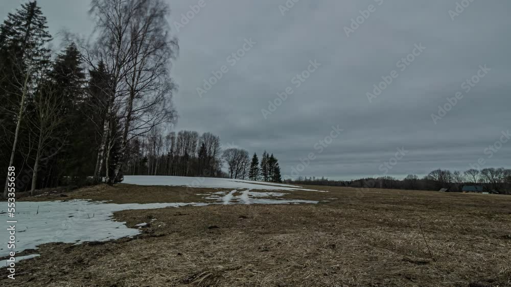 Poster timelapse of afternoon clouds over semi frosted hillside with setting sun. static shot