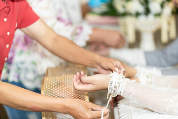 Obraz na płótnie Canvas Sacred thread tied in a Thai wedding ceremony The hands of the bride and groom are tied with threads. Thai wedding culture with Oraporn