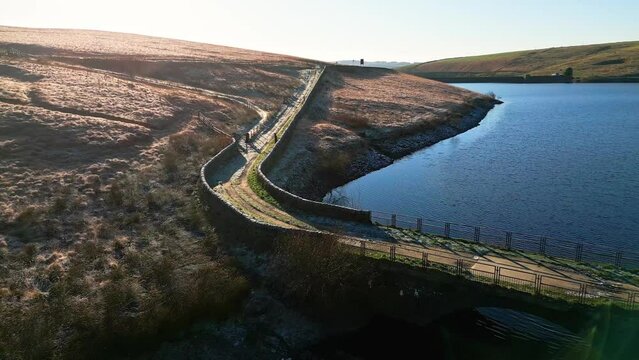 Aerial View of a reservoir, lake with surrounding moorlands set on Saddleworth moor England, showing small pathway and bridge