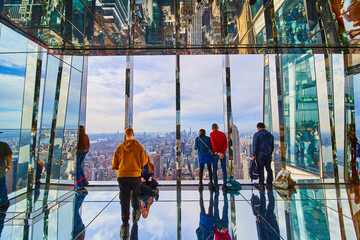 Glass mirror room overlook with tourists high up over New York City looking at Manhattan skyline