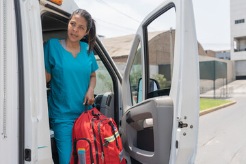 Woman getting out of an ambulance with a first aid bag