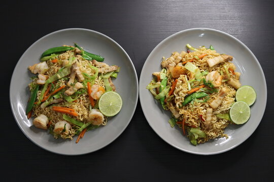Pancit Canton Chow Mein Stir Fry Instant Noodles with Shrimp, Pork Belly, Cabbage, Carrots, Snap Peas, Lime - Top Down View