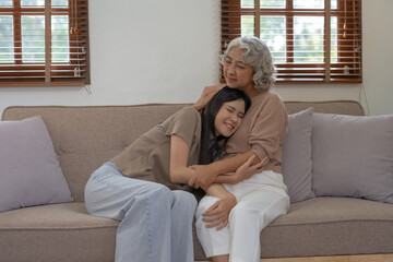 Asian mother and daughter spend the holidays in their living room, expressing their love by embracing each other at home happily and warmly.