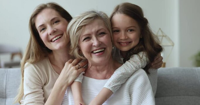 Older granny enjoy embraces and time with loving grown up daughter and granddaughter, close up view. Portrait of overjoyed multi generational family, understanding, harmonic relations, ties, affection