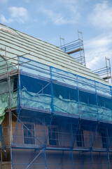 Home construction.Scaffolding in a protective blue grid against a cloudy sky. Preparatory building work. Building materials and the process of repair a house. 