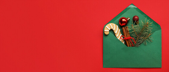 Envelope with Christmas cookie and decor on red background with space for text, top view