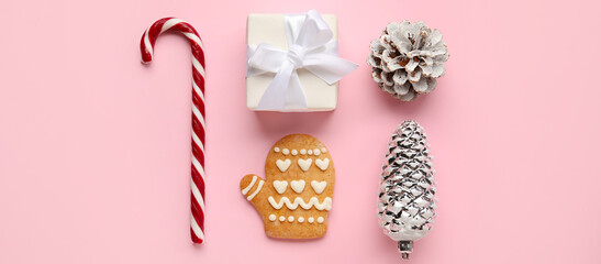 Beautiful Christmas composition with candy cane, gift, cones and cookie on pink background