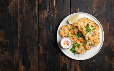 Cauliflower steaks on wooden background, view from above, copy space