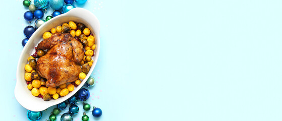 Baking dish with tasty roasted chicken, potatoes and Christmas balls on light blue background with space for text