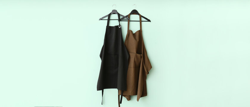 Clean aprons hanging on light blue wall
