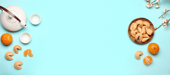 Tasty fortune cookies with tangerines and Chinese tea on light blue background with space for text