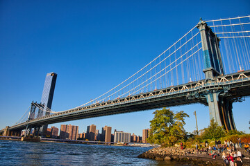 View of entire Brooklyn Bridge from low angle with waters and New York City in background