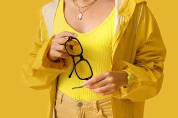 Fashionable African-American woman holding stylish sunglasses on color background © Pixel-Shot