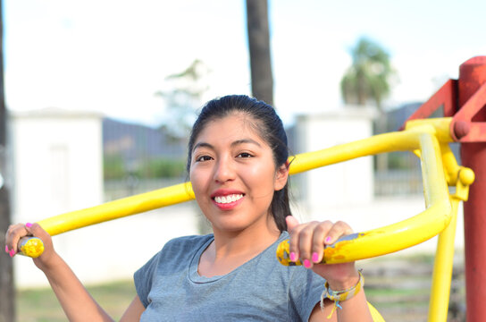 Latina morena haciendo gimnasia en un parque. Joven mujer estudiante sonriendo y feliz en un juego	