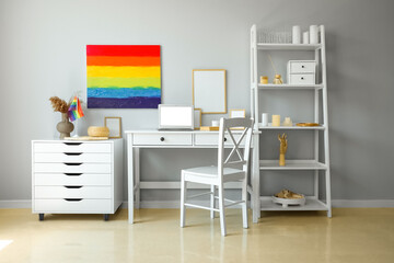 Interior of light office with workplace, LGBT flag and painting