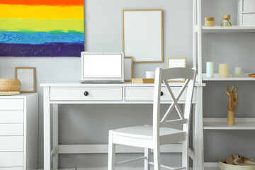Interior of light office with workplace and rainbow painting