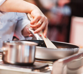 Cooks prepare meals on the stove in the kitchen of the restaurant or hotel.