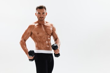Obraz premium Man athletic body bodybuilder posing with dumbbells with naked torso abs full-length in the background, fitness class. Advertising, sports, active lifestyle, competition, challenge concept. 