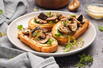 Plate of tasty toasts mushrooms and bowl of sauce on grunge background