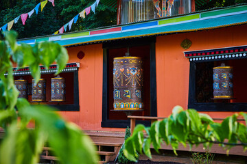 Temple with ornate prayer wheels through the leaves