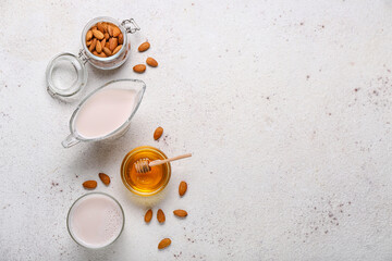 Obraz na płótnie Canvas Gravy boat, glass of healthy almond milk, nuts and honey on light background
