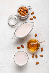 Gravy boat, glass of healthy almond milk, nuts and honey on light background
