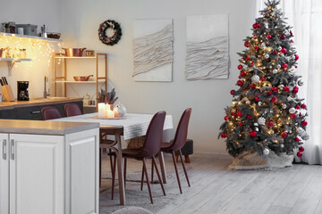 Interior of kitchen with glowing Christmas tree, counters and dining table