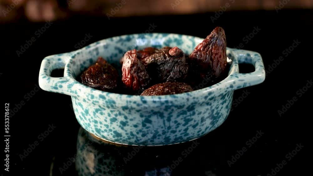 Poster Dried mission figs in a glass bowl play with light on black background