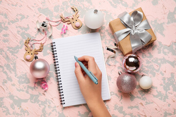 Woman writing in blank notebook, Christmas toys and gift on grunge background