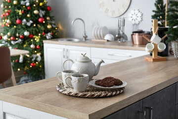 Teapot with cups and Christmas cookies on counter in kitchen