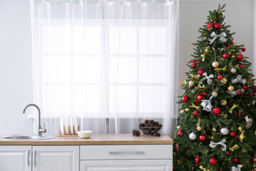 Interior of kitchen with Christmas tree, white counters and window