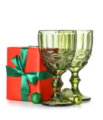 Glasses with Christmas balls and gift on white background