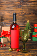 Bottle of wine with glass and Christmas balls on dark wooden background, closeup