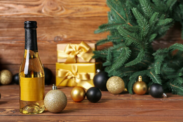 Bottle of wine with Christmas ball on wooden table, closeup