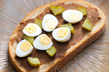 cracklings spread with pickled cucumber and boiled egg on slice of bread