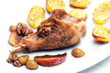 poultry leg baked with fruit and walnuts served with fried potatoes